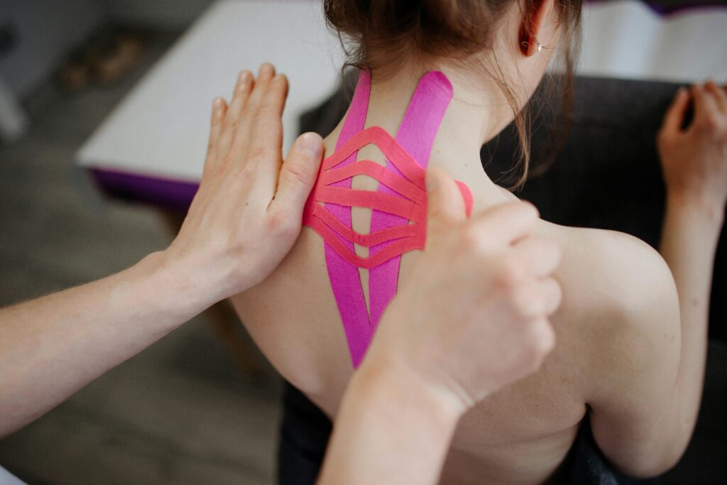 A close-up image of kinesio tape being applied to a person's back, showcasing healthcare and treatment.